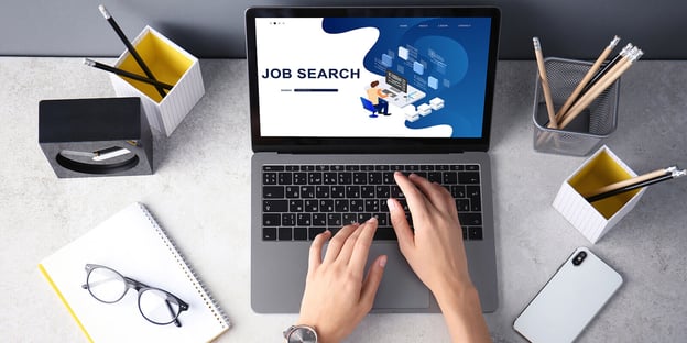 Hands typing on a laptop that says job search