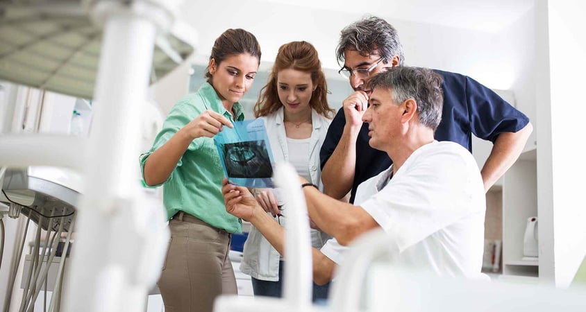 Dentists looking at x rays with team.